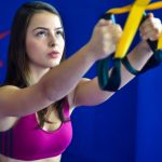 Focused woman using suspension training straps during workout indoors.